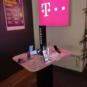 Samsung Smartphones auf einem Präsentationstisch im Telekom Shop mit Congstar Mobilfunktarif-Poster.